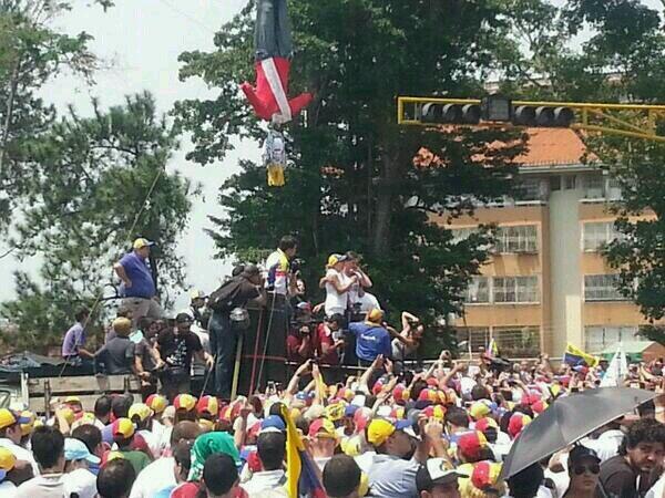 Sous l'effigie d'un chaviste pendu haut et court, la dirigeante de droite María Corina Machado tient un discours dans l'État de Tachira (région sous influence des paramilitaires colombiens et des mafias de la contrebande, où ont débuté les violences de février 2014). 