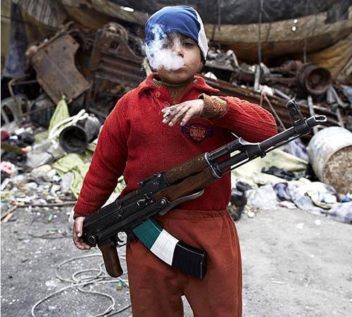 Un enfant-soldat âgé de seulement 7 ans ,fume une cigarette d'un air menaçant.Membre de la Syrian Free Army ,soutenue par les États-Unis d'Amérique,cet enfant a du subir un lavage de cerveau.