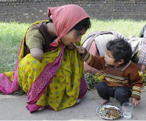 Un jeune garçon aide sa mère à se nourrir au moyen de baguettes.Sa mère qui a perdu ses deux bras malheureusement.