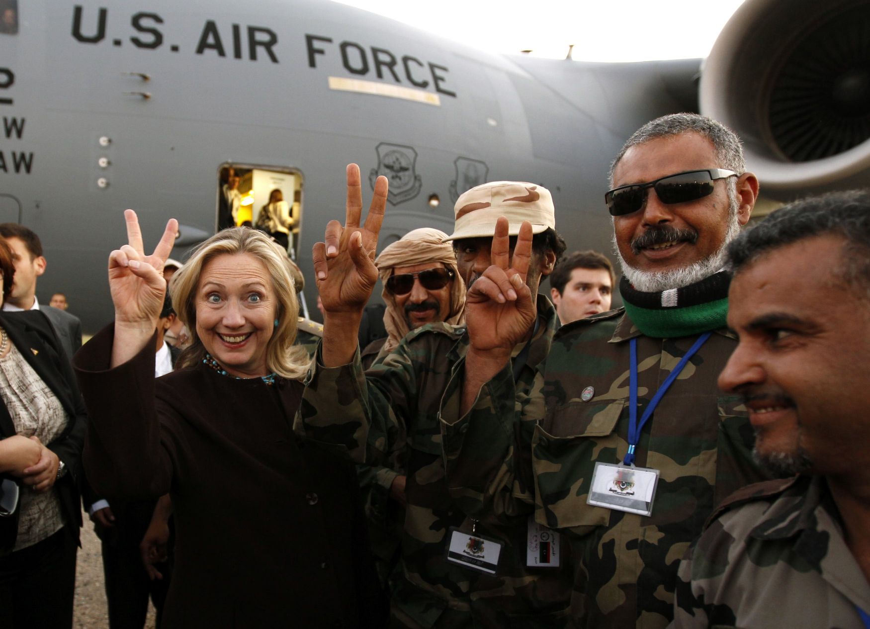 Hillary Clinton est cette politicienne américaine qui a particulièrement aidé à l'instauration de la "Pax Americana" en Lybie.On la voit ici,le 19 octobre 2011,faisant son signe illuminati de la victoire,entourée des mercenaires terroristes qu'elle a grassement payé pour éliminer le Grand Guide Lybien Khadafi et mettre ce pays en ruines. 